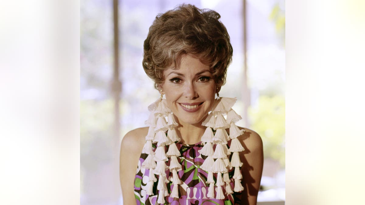 Barbara Rush lächelt und trägt ein farbenfrohes Kleid.