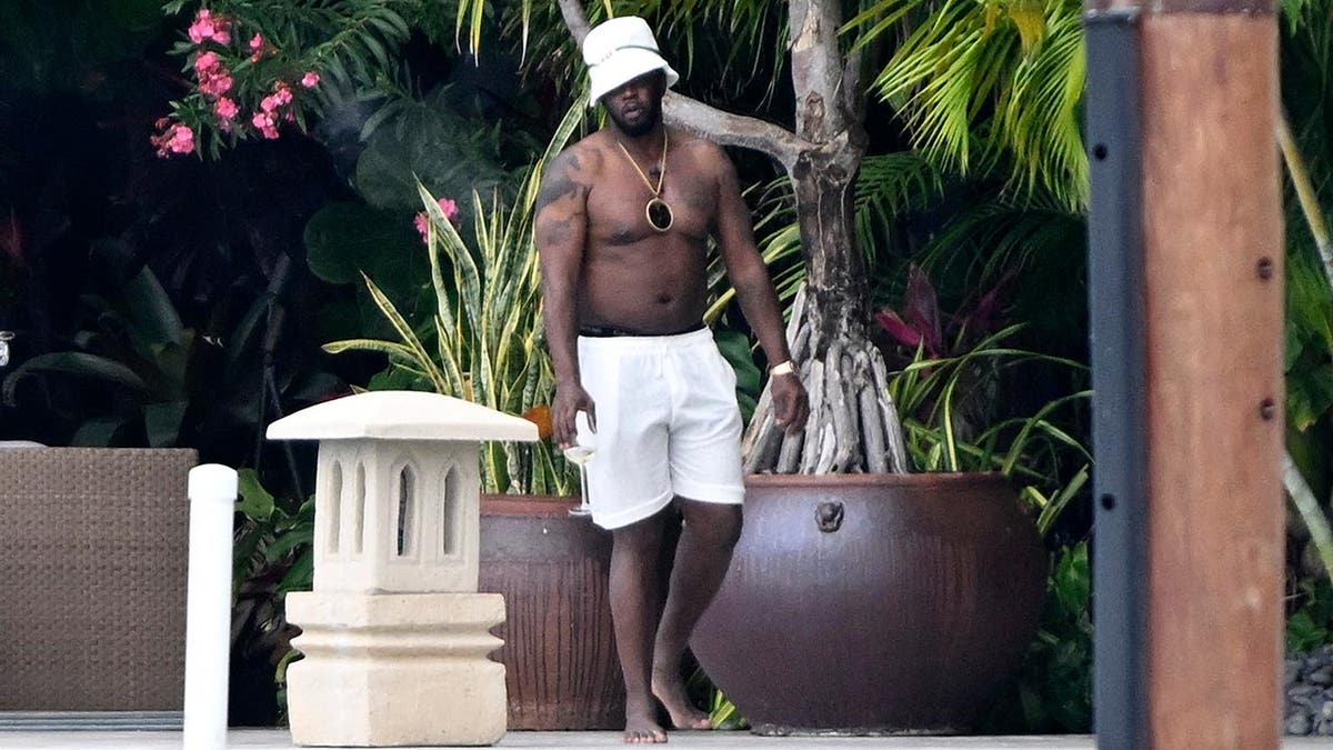 P Diddy steht ohne Hemd und mit einem Weinglas an seinem Platz am Wasser seines Hauses in Miami