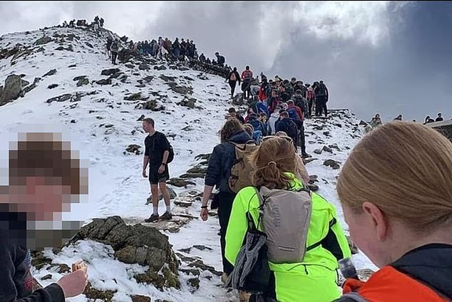 Icy ground and snow-capped mountains have not deterred dogged explorers trekking to Snowdon in Wales - with some even wearing shorts to battle the elements