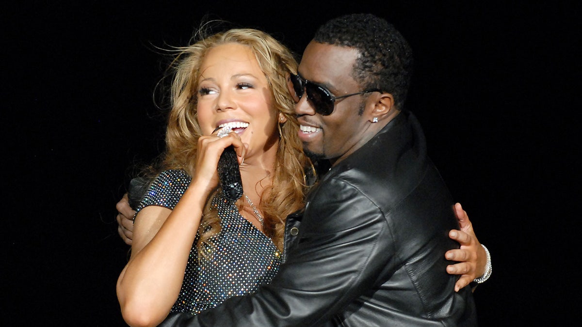 Singer Mariah Carey holds a microphone on stage with Diddy