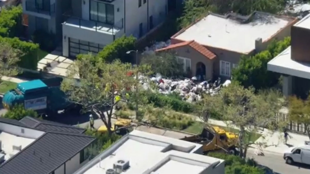 Luftaufnahme eines Hauses in LA mit Müllbergen auf dem Rasen vor dem Haus
