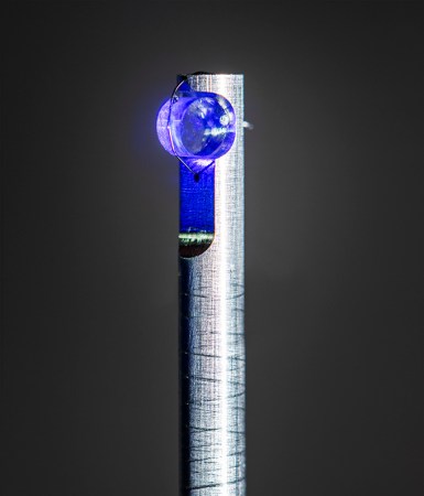 Ein Kristall aus Kalziumfluorid, der durch blaues Licht beleuchtet und auf einem Pfosten montiert wird