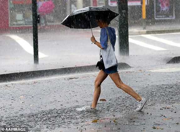 A woman steps in a puddle as she crosses the road during heavy rain in Sydney, Tuesday, Feb. 7, 2017. (AAP Image/David Moir) NO ARCHIVING