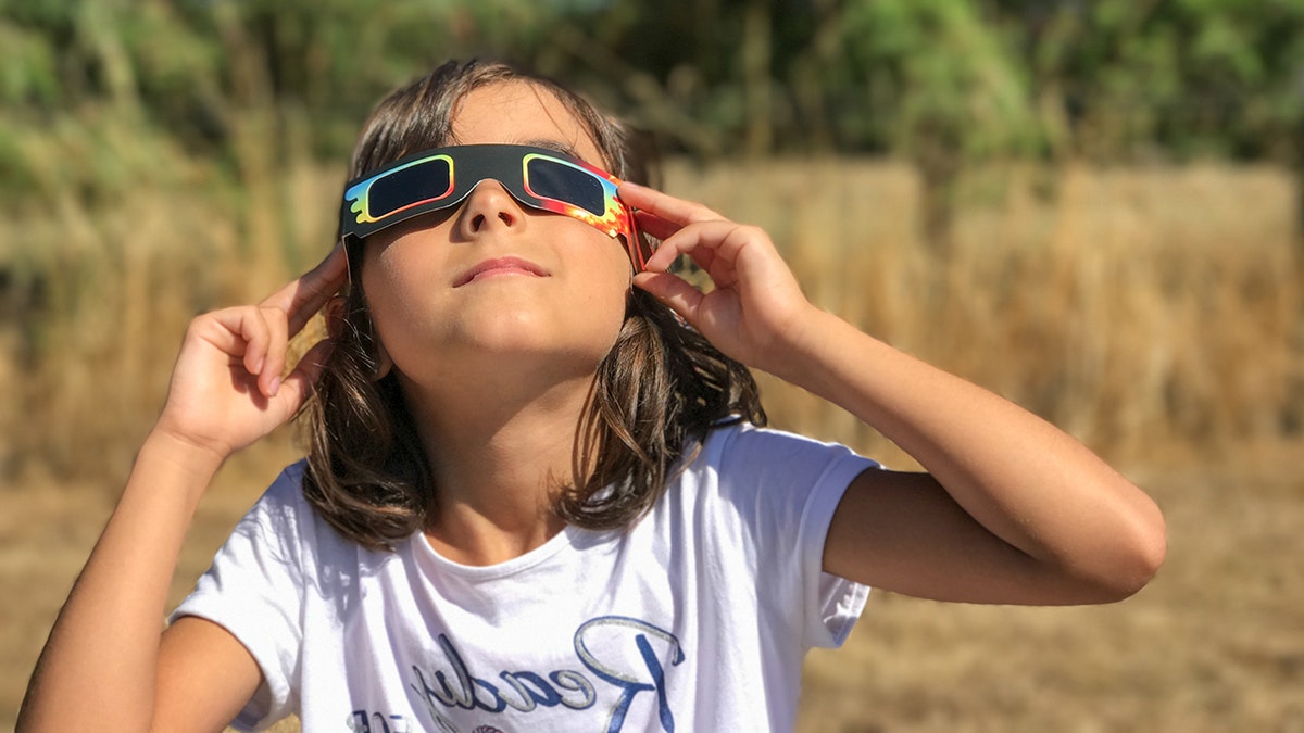 Junges Mädchen blickt durch eine Brille auf die Sonnenfinsternis