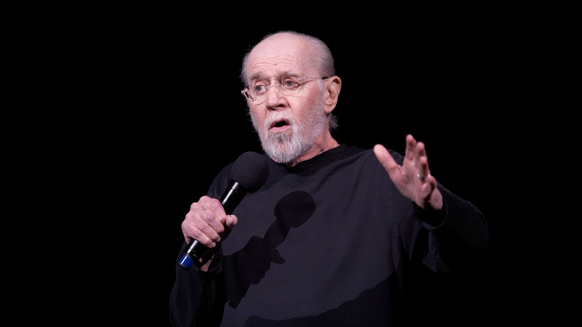 George Carlin auf der Bühne mit einem Mikrofon