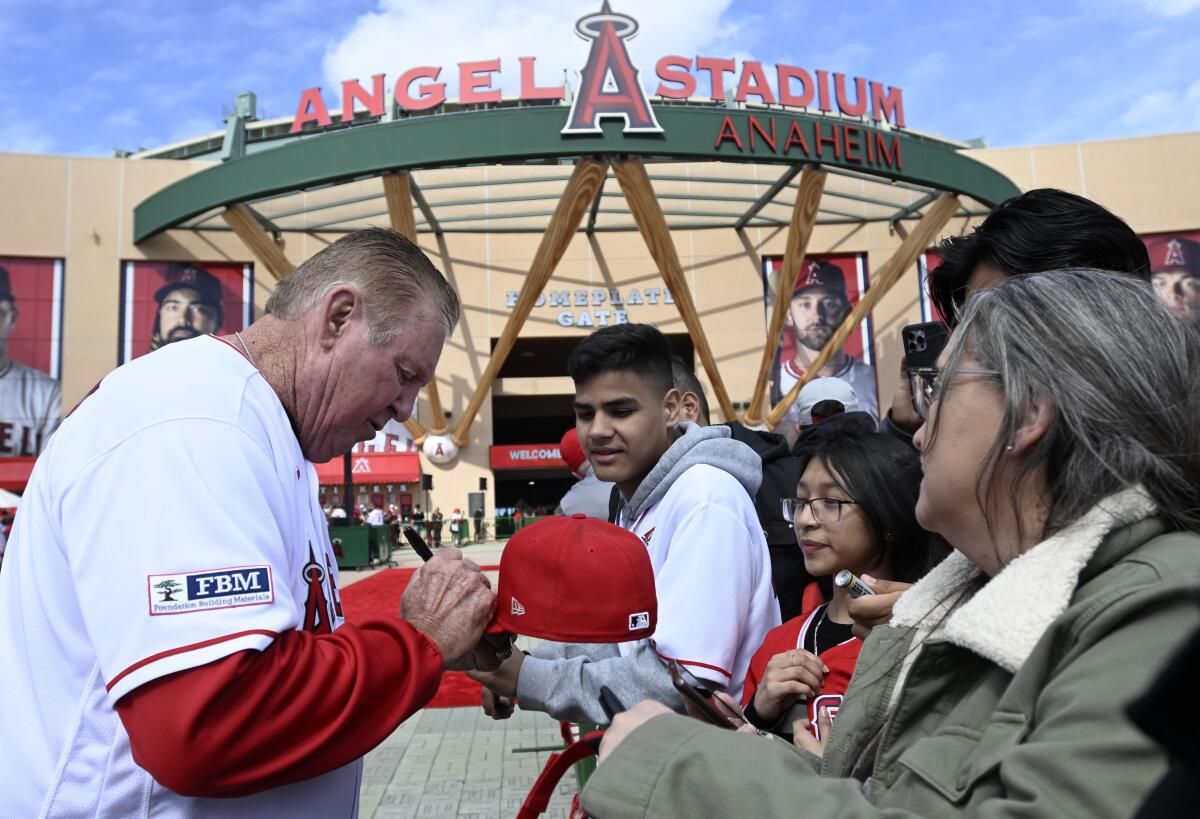 Der ehemalige Schlagmanntrainer der Angels und Dodgers-Spieler Mickey Hatcher gibt vor dem Spiel am Freitag Autogramme für einen Fan.