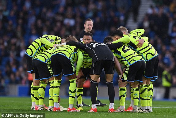 Arsenal players form a group huddle on the pitch before the start of the second half of the English Premier League football match between Brighton and Hove Albion and Arsenal at the American Express Community Stadium in Brighton, southern England on April 6, 2024. (Photo by Glyn KIRK / AFP) / RESTRICTED TO EDITORIAL USE. No use with unauthorized audio, video, data, fixture lists, club/league logos or 'live' services. Online in-match use limited to 120 images. An additional 40 images may be used in extra time. No video emulation. Social media in-match use limited to 120 images. An additional 40 images may be used in extra time. No use in betting publications, games or single club/league/player publications. /  (Photo by GLYN KIRK/AFP via Getty Images)