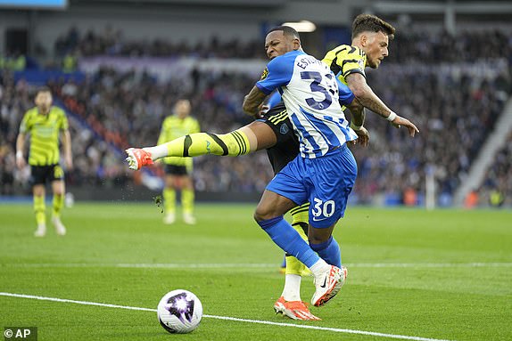 Brighton's Pervis Estupinan, centre, challenges for the ball with Arsenal's Ben White during the English Premier League soccer match between Brighton and Hove Albion and Arsenal at the American Express Community Stadium in Brighton, England, Saturday, April 6, 2024. (AP Photo/Dave Shopland)