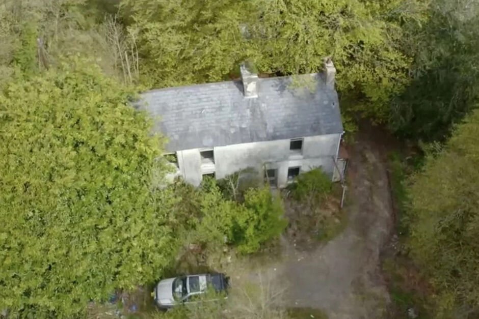 Vogelperspektive auf ein altes graues Bauernhaus im Wald