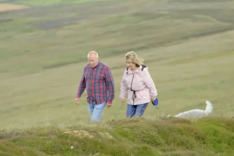 Ältere Männer und Frauen gehen mit Hund auf Feldern spazieren