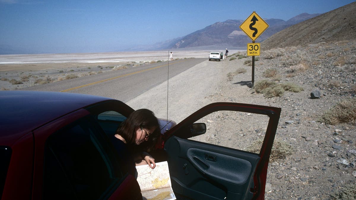 Eine Frau liest eine Karte, während sie am Straßenrand anhält