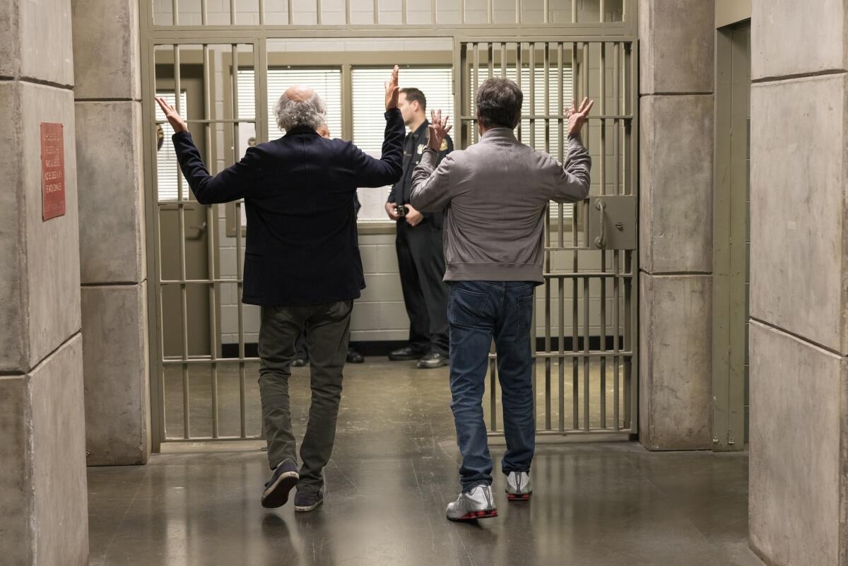 Zwei Männer, von hinten gesehen, wie sie durch den Flur eines Gefängnisses gehen.