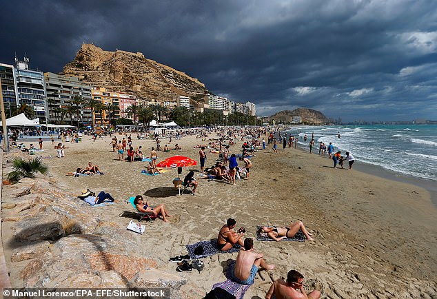 Touristen verbringen Zeit am Strand von Postiguet an einem bewölkten Tag in der Stadt Alicante, Region Comunidad Valenciana, Ostspanien, 28. März 2024