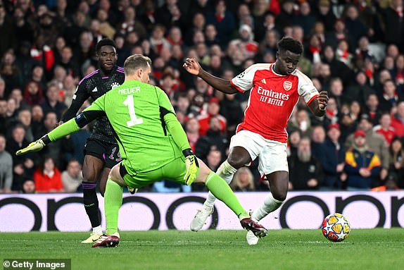 LONDON, ENGLAND - APRIL 09: Bukayo Saka of Arsenal is tackled by Manuel Neuer of Bayern Munich during the UEFA Champions League quarter-final first leg match between Arsenal FC and FC Bayern MÃ¼nchen at Emirates Stadium on April 09, 2024 in London, England. (Photo by Shaun Botterill/Getty Images)