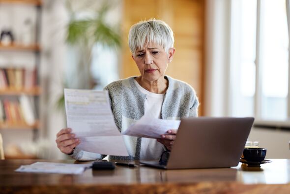 Besorgte ältere Frau, die zu Hause ihre Rechnungen über den Laptop bezahlt.