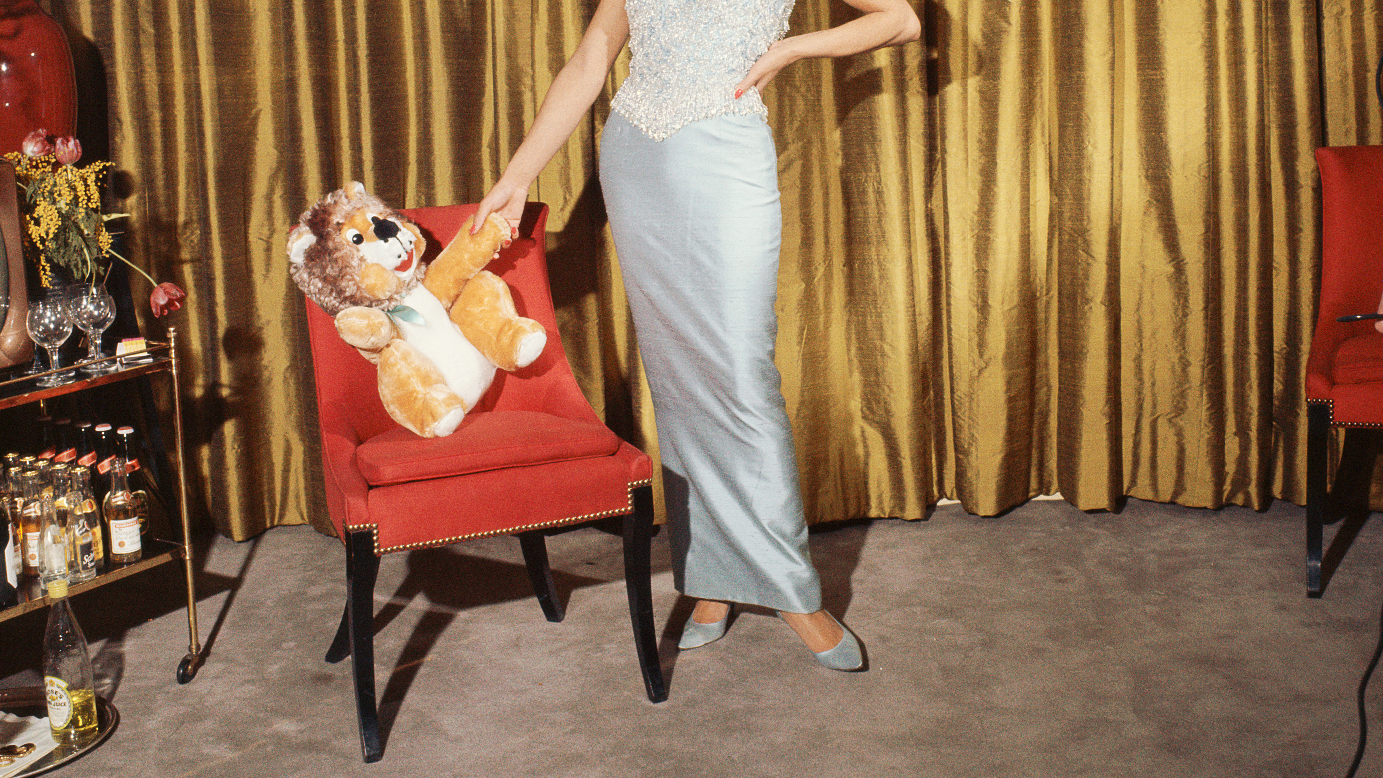 Ein Vintage-Foto einer Frau, die ein bodenlanges Kleid trägt und ein Stofftier in der Hand hält