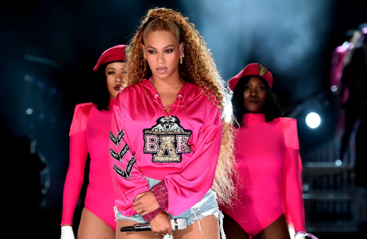 Beyoncé tritt in einem rosa Sweatshirt mit der Aufschrift „ΒΔΚ“ und abgeschnittenen Jeans auf der Bühne von Coachella auf. 