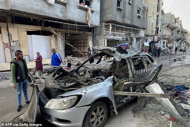 Onlookers check the car in which three sons of Hamas leader Ismail Haniyeh were reportedly killed in an Israeli air strike in al-Shati camp, west of Gaza City