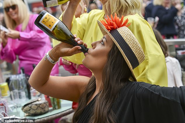 A woman is pictured downing a bottle of bubbly at the event in Liverpool today