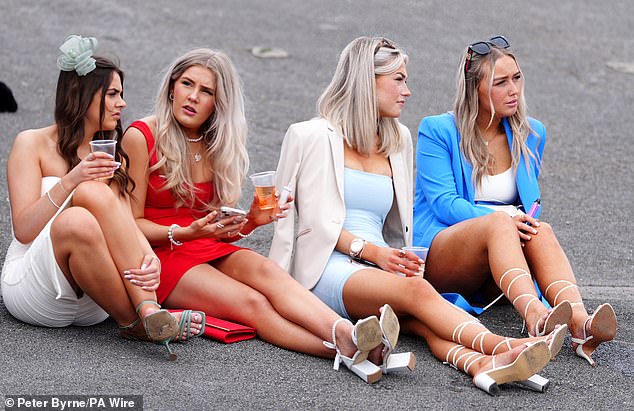 A group of racegoers sat down on the pavement to enjoy a chat while sipping their drinks