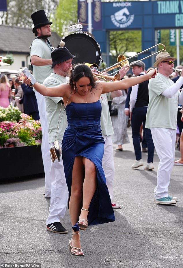 A woman dressed in a navy dress is pictured showing off her moves as she dances to a band