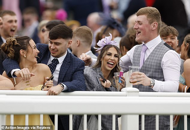 Four young revellers look in high spirits as they enjoy the race at Aintree today