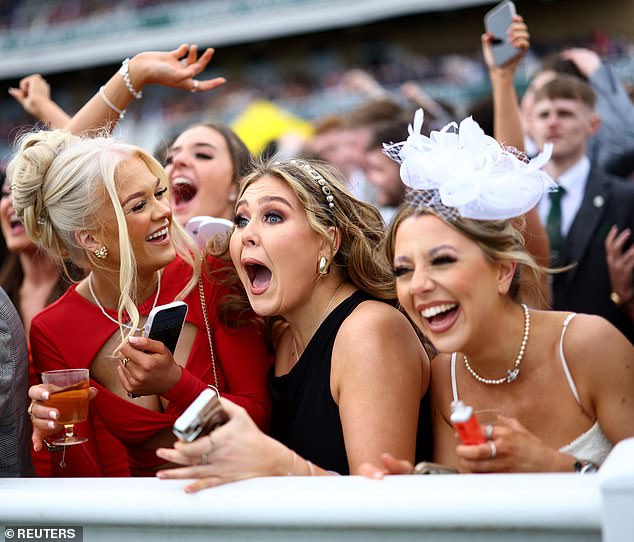 Three girls look shocked as they react to the race at Aintree today