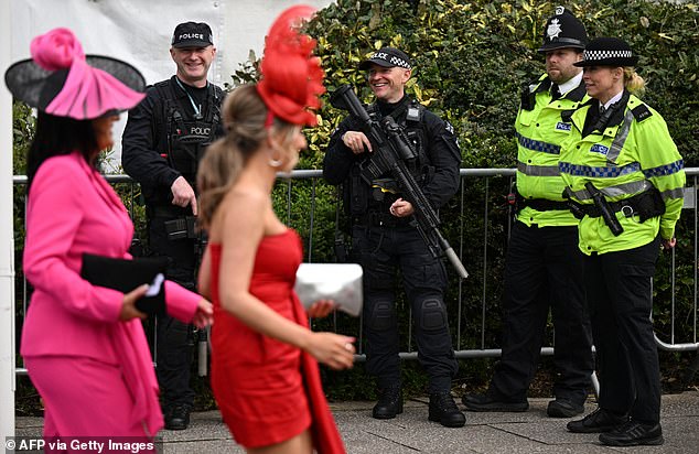 Police officers look in high spirits and smile as revellers in bold outfits enter the event in Liverpool today