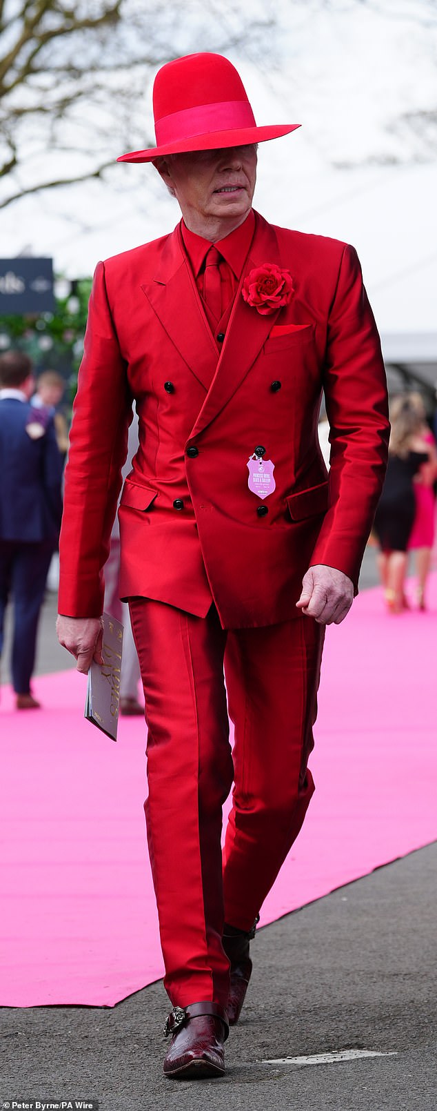 A reveller is pictured in a shiny red suit, complete with a hat, as he makes his arrival at Aintree Racecourse