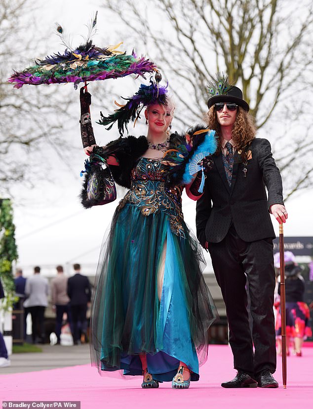 Two revellers strutted along the pink carpet covered in feathers and dressed in  peacockesque ensembles as they compete for the cash prize on Ladies Day