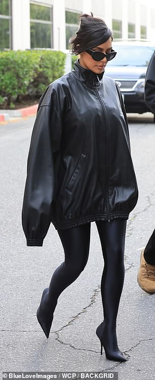 Dazu trug sie eine übergroße, hochgeschlossene schwarze Lederjacke mit dem Namen und dem Logo des Modehauses auf einer Seite