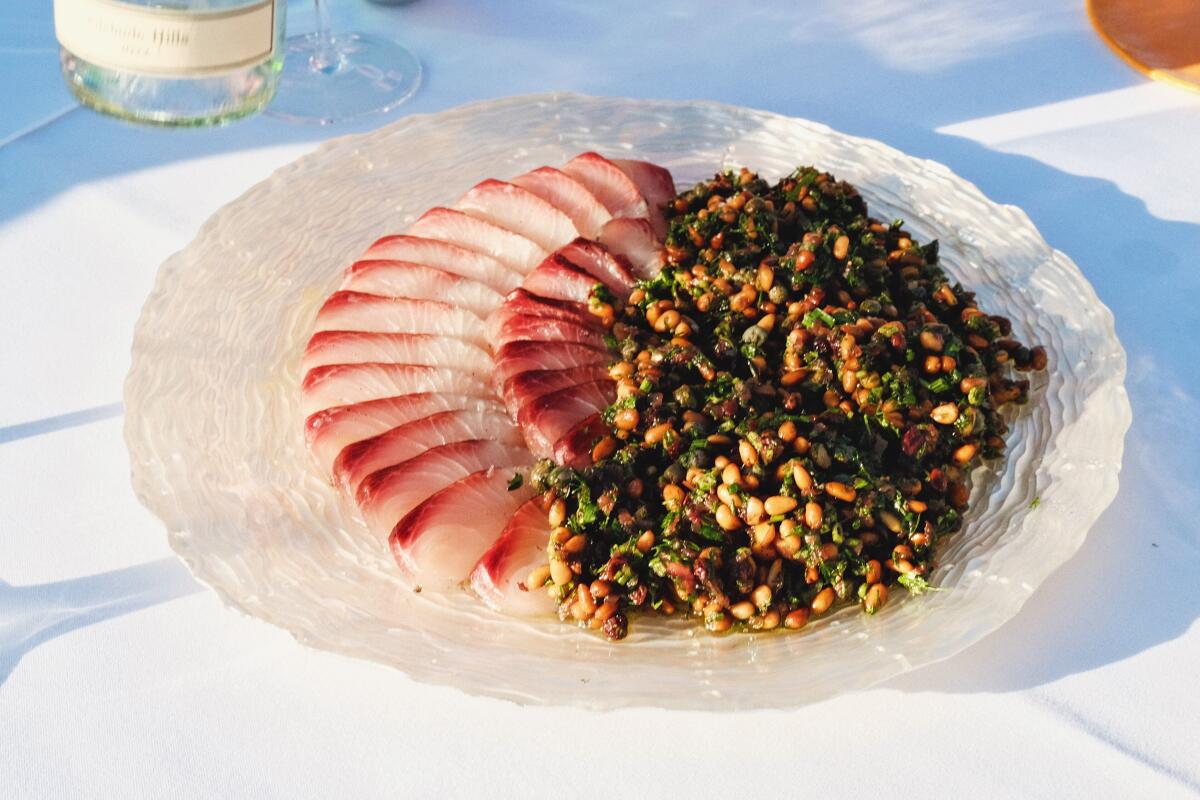 Ein Teller mit geschnittenem Hiramasa mit Feigenblatt- und Pinienkernsalat.