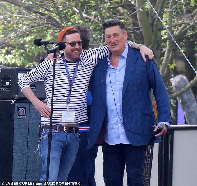 He opted for further accessorising his look with a bright orange hat and adorned a huge grin on his face as he put his arm around his pal Tony Hadley
