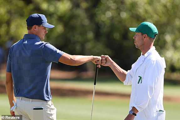 Golf - The Masters - Augusta National Golf Club, Augusta, Georgia, U.S. - April 12, 2024 Sweden's Ludvig Aberg bumps fists with his caddie on the green on the 18th hole after completing his second round REUTERS/Mike Blake