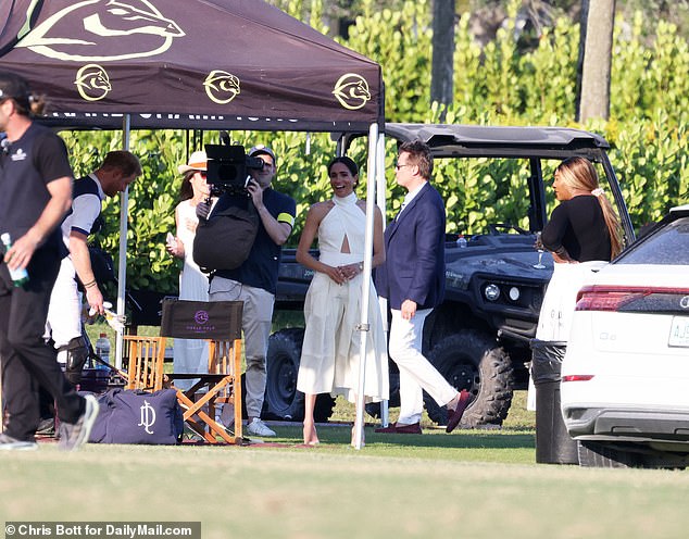 Meghan is seen laughing in this picture next to film crews documenting the couple