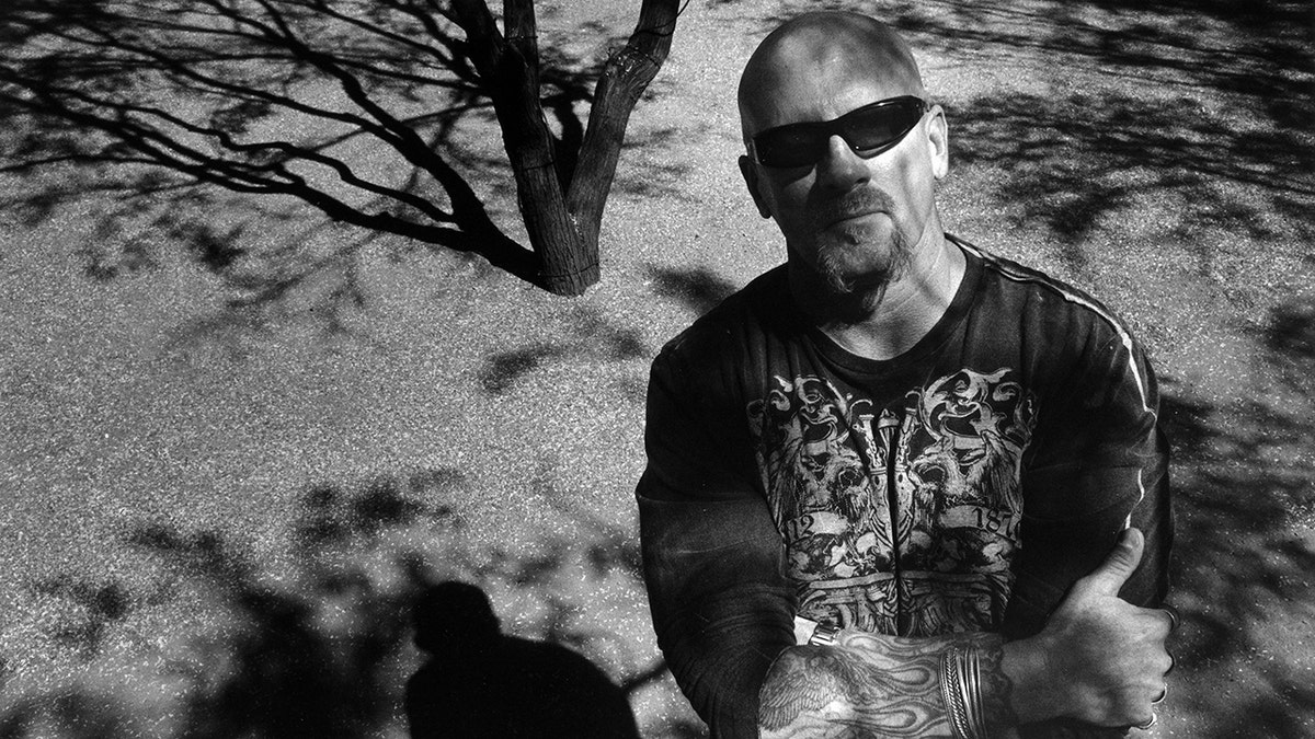 Jay Dobyns in Schwarzweißfoto steht vor einem Baum