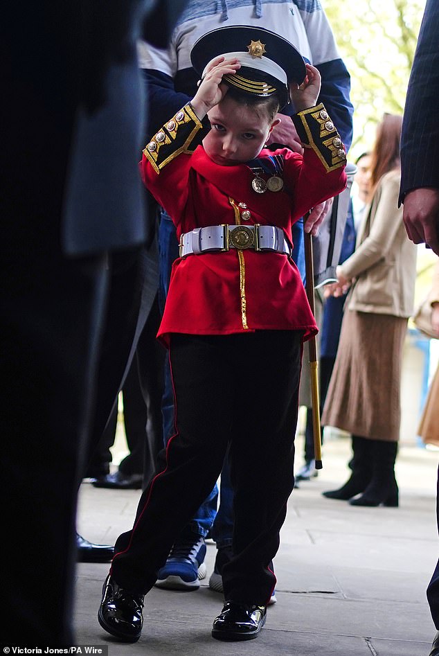 Ein kleiner Junge in Replik-Uniform schließt sich den Mitgliedern der Scots Guards an, die sich vor der Black Sunday Parade in der Kapelle des Guards Museum in Wellington Barracks versammeln