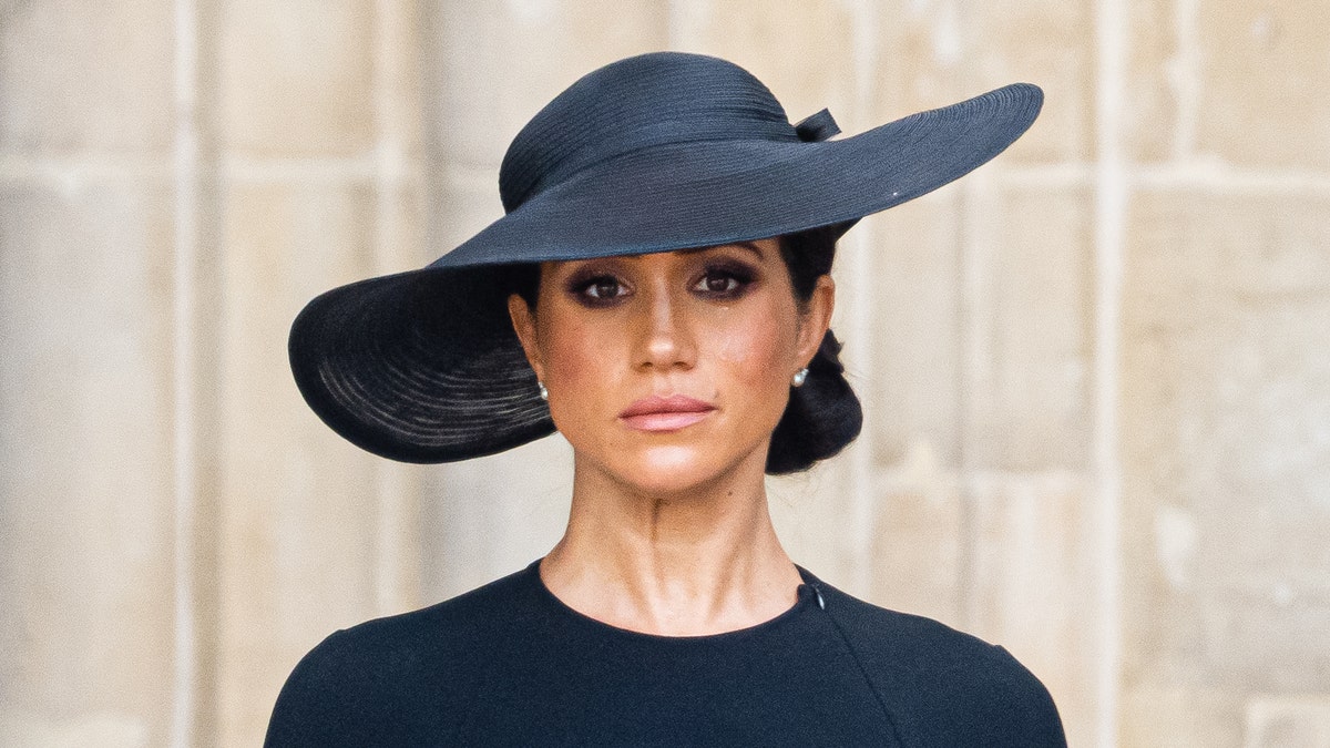 Meghan Markle trägt bei der Beerdigung von Königin Elizabeth ein schwarzes Kleid und einen schwarzen Hut.