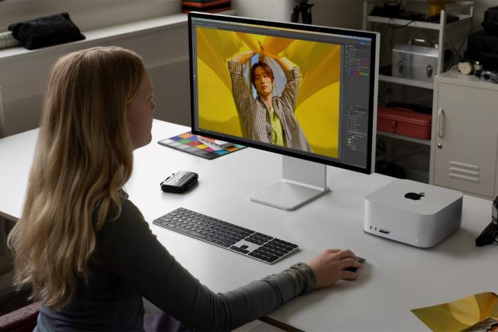 Eine Frau sitzt an einem Schreibtisch mit dem M2 Mac Studio darauf.