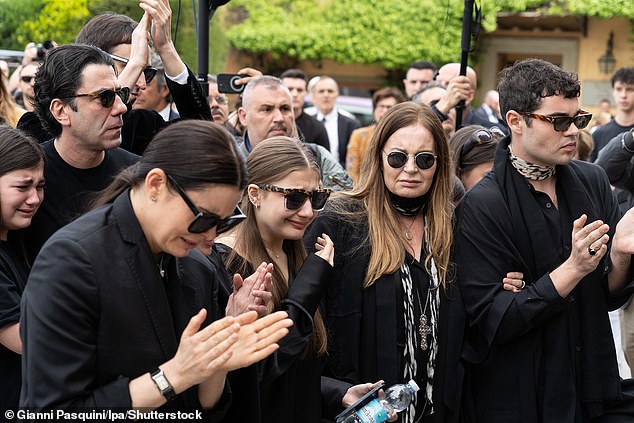 Mourners at the funeral are snapped weeping, as they clap while the iconic designer's coffin passes them