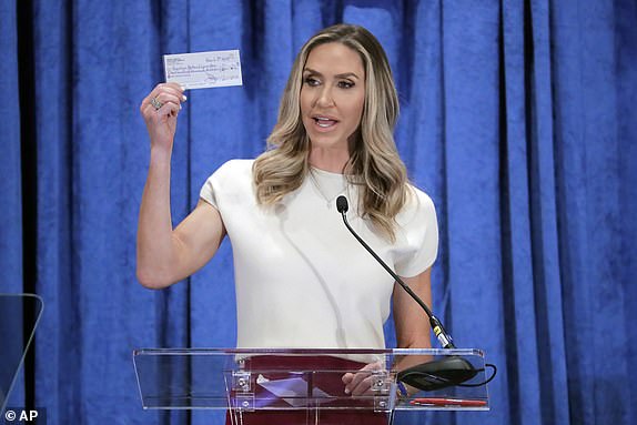Lara Trump, the newly-elected co-chair of the Republican National Committee, holds up a donation check as she gives an address during the general session of the RNC Spring Meeting Friday, March 8, 2024, in Houston. (AP Photo/Michael Wyke)