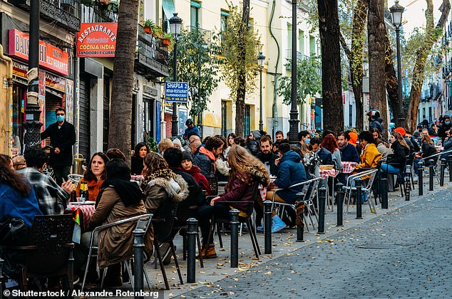 Attraction: People enjoy drinks at a cafe in Madrid. There are around 303,000 Britons living in Spain on visas that are not affected by last week's announcement