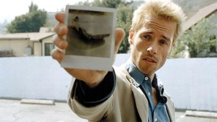 Guy Pearce als Leonard Shelby zeigt in Memento ein Polaroid in die Kamera.