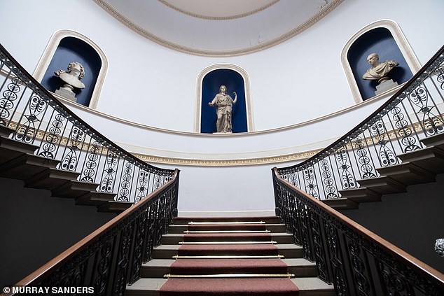 The sweeping main staircase features Greek and Roman statues and busts