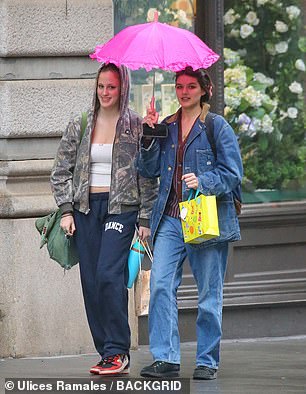 The pair stayed dry beneath a garish pink umbrella, held by Suri