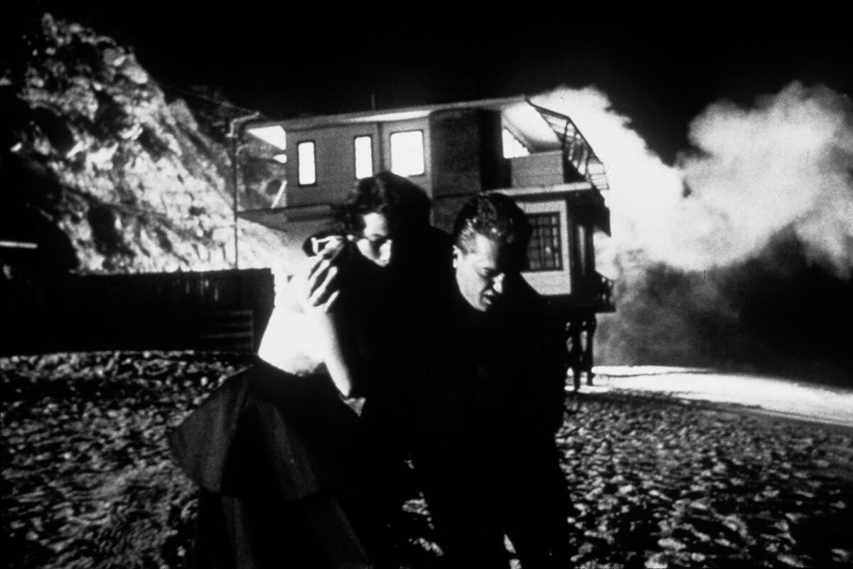 Eine Frau und ein Mann fliehen aus einem brennenden Haus.