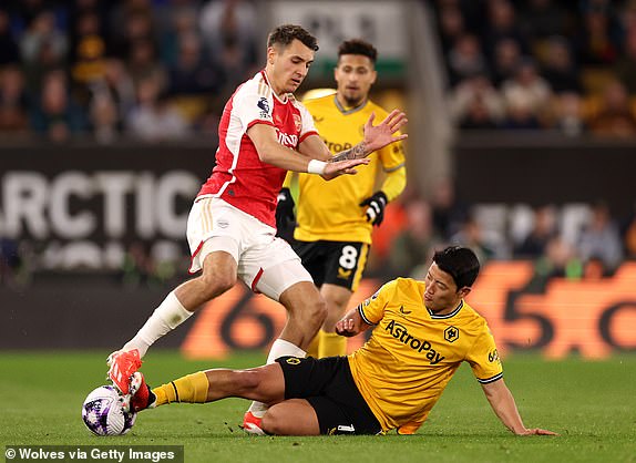 WOLVERHAMPTON, ENGLAND - APRIL 20: Jakub Kiwior of Arsenal is challenged by Hwang Hee-Chan of Wolverhampton Wanderers during the Premier League match between Wolverhampton Wanderers and Arsenal FC at Molineux on April 20, 2024 in Wolverhampton, England. (Photo by Jack Thomas - WWFC/Wolves via Getty Images)