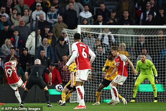 Arsenal's Belgian midfielder #19 Leandro Trossard (L) shoots to score the opening goal of the English Premier League football match between Wolverhampton Wanderers and Arsenal at the Molineux stadium in Wolverhampton, central England on April 20, 2024. (Photo by HENRY NICHOLLS / AFP) / RESTRICTED TO EDITORIAL USE. No use with unauthorized audio, video, data, fixture lists, club/league logos or 'live' services. Online in-match use limited to 120 images. An additional 40 images may be used in extra time. No video emulation. Social media in-match use limited to 120 images. An additional 40 images may be used in extra time. No use in betting publications, games or single club/league/player publications. /  (Photo by HENRY NICHOLLS/AFP via Getty Images)