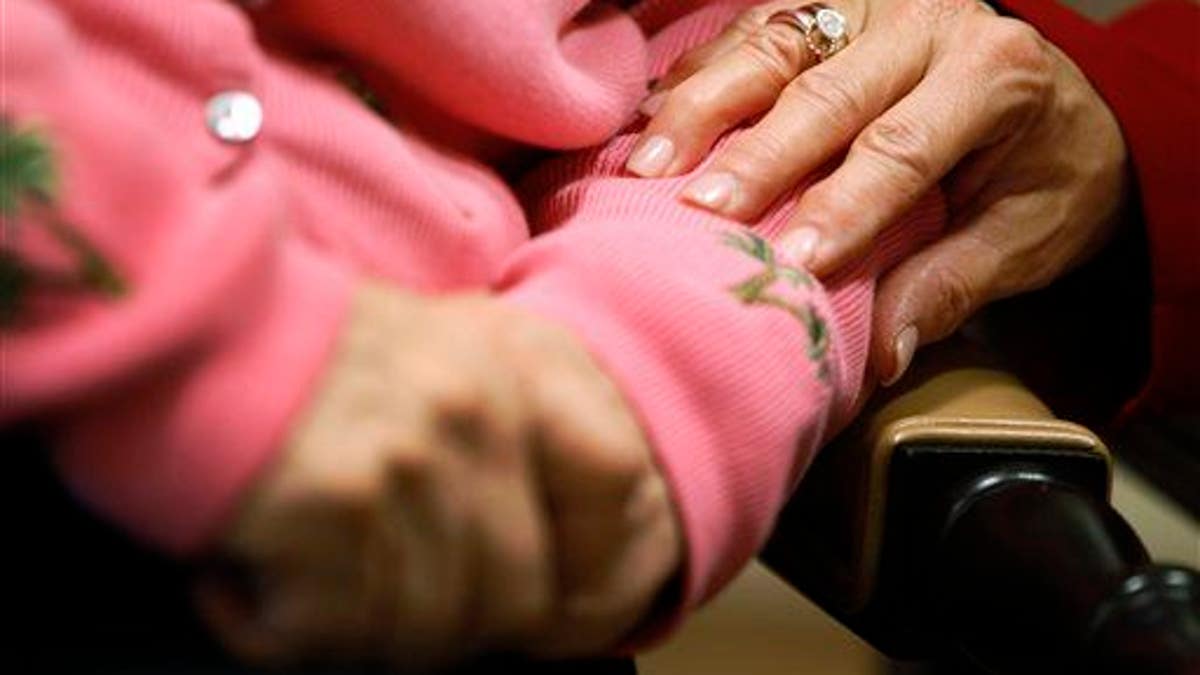 Eine Mitarbeiterin einer Einrichtung für betreutes Wohnen mit Alzheimer-Krankheit legt ihre Hand auf den Arm eines Bewohners
