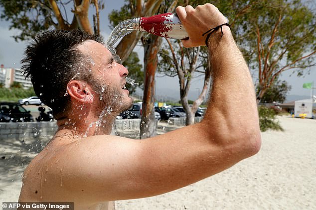 Ein Strandgänger gießt sich am 19. Juli 2023 am Ricanto-Strand in Ajaccio auf der französischen Insel Korsika Wasser ins Gesicht, um sich zu erfrischen, während Europa von einer großen Hitzewelle heimgesucht wird